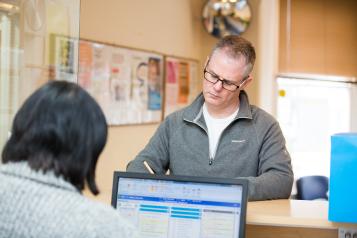 person stood at reception speaking to receptionist