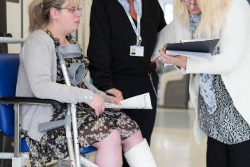 woman sat down in hospital speaking to two people