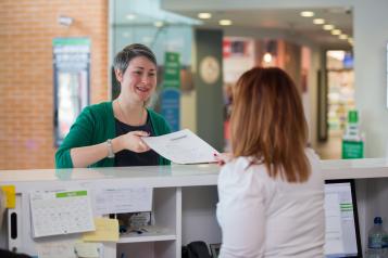 woman handing form to receptionist