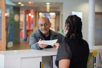 man speaking to receptionist in hospital