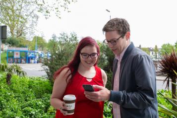 two people stood outside looking at phone