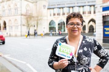 woman stood outside holding leaflet