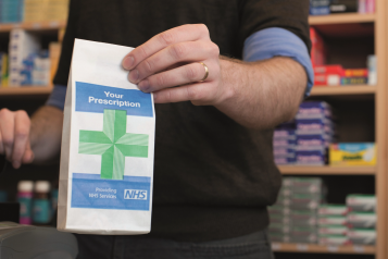 Pharmacist holding an NHS prescription bag
