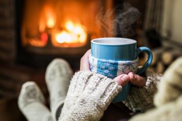 Person wearing white gloves and holding a mug of a hot drink