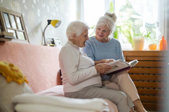 Senior woman and her adult daughter looking at photo album together