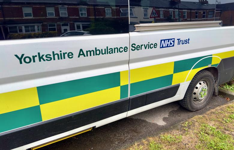 Side view of a Yorkshire Ambulance Service NHS Trust patient transport vehicle parked on a residential street