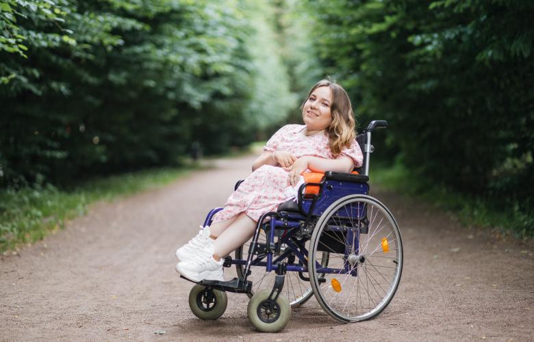 Young lady with spinal muscular atrophy spending warm summer day on fresh air. 