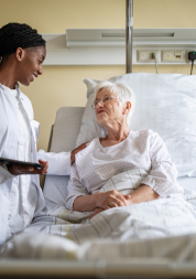A lady in a hospital bed with a doctor visiting her