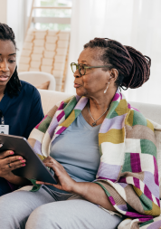 A photo of a healthcare professional talking with a woman and completing a survey.